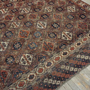 Geometric pattern rug in muted rust, navy, and cream on weathered wooden floors.