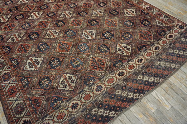 Geometric pattern rug in muted rust, navy, and cream on weathered wooden floors.