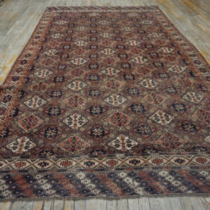 Rectangular rug featuring repeating geometric diamonds in muted brown, rust, and navy blue on a wood floor.