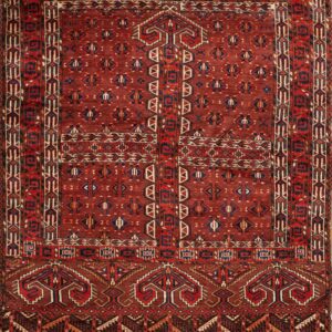 Traditional deep red rug with intricate geometric motifs and striped borders in blue, cream, and red.