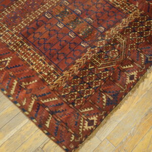 Geometric rug in rust red, navy blue, and cream on a light wooden plank floor.