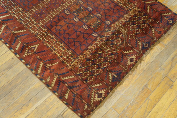Geometric rug in rust red, navy blue, and cream on a light wooden plank floor.