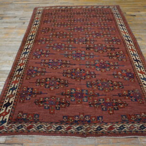 Rust-red rug featuring rows of tribal geometric patterns in blue, red, and ivory on a wood floor.