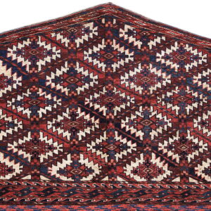 Deep red rug with a peaked shape and repeating blue and cream geometric medallions.