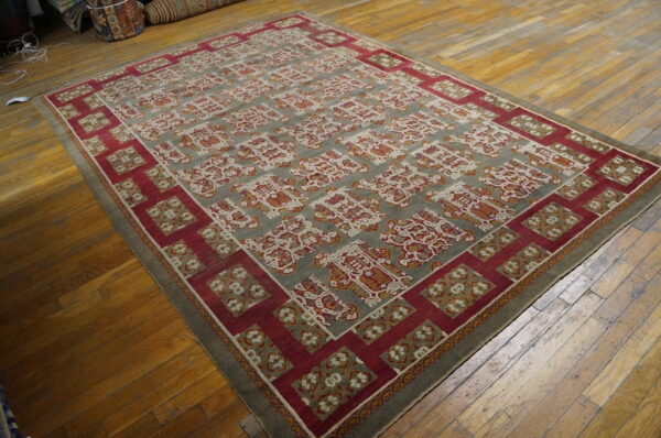 A large rug with red and gray geometric patterns rests on wide plank wooden flooring.