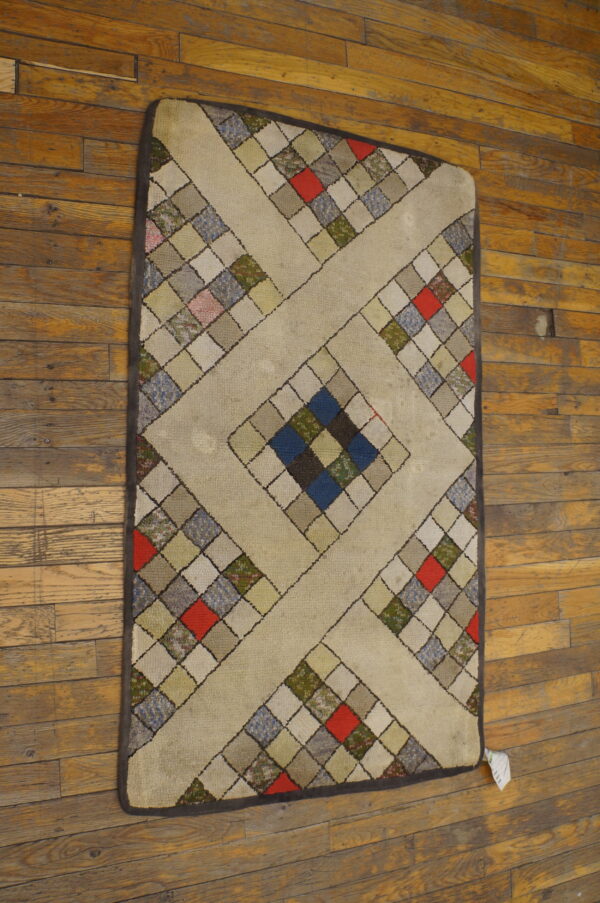 Beige rug with a colorful geometric square patchwork design, including red and blue, on distressed wood planks.