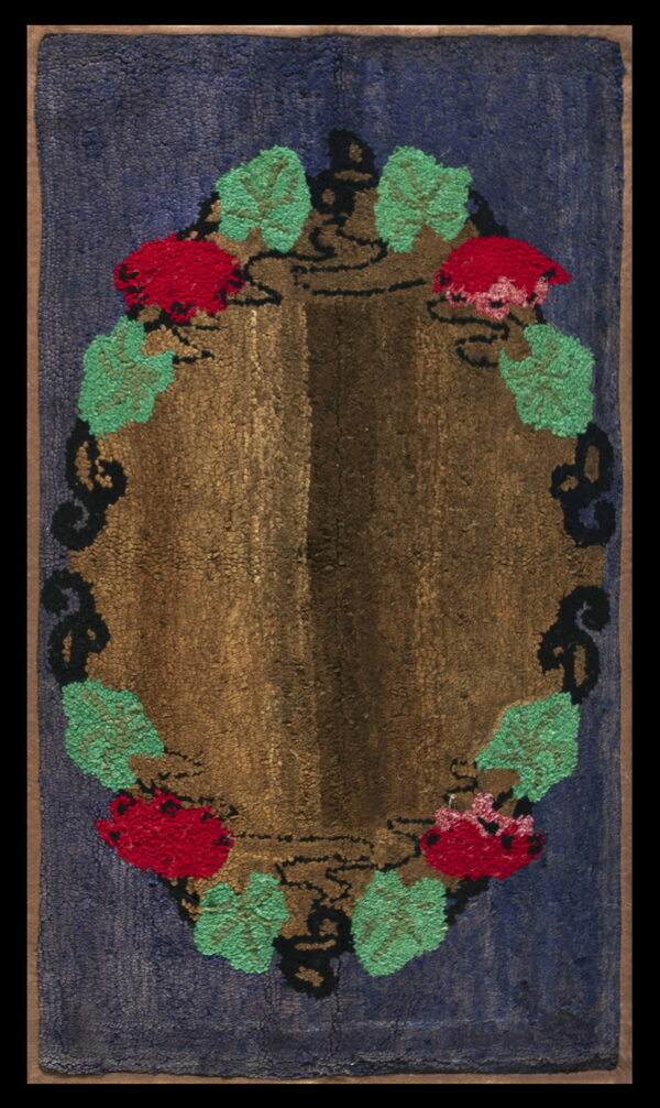 Navy blue hooked rug with a central brown oval medallion decorated with red flowers and green leaves.