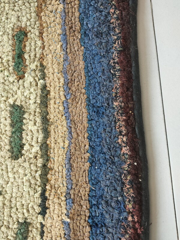 High-pile looped rug showing abstract stripes in tan, blue, burgundy, and cream against white tiled flooring.