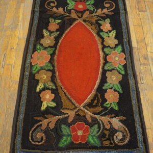 Hooked runner rug featuring a bright red center oval and multi-colored floral designs on wood flooring.