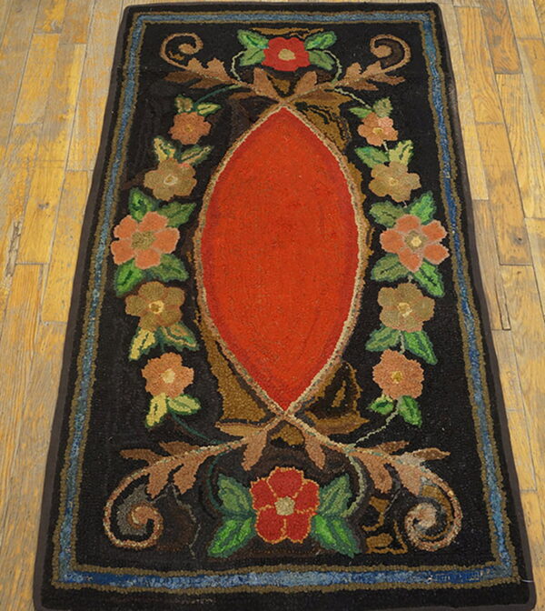 Hooked runner rug featuring a bright red center oval and multi-colored floral designs on wood flooring.