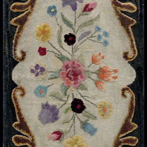 Sculpted rug featuring a multicolored floral bouquet on a light center field framed by dark brown scrolling motifs.