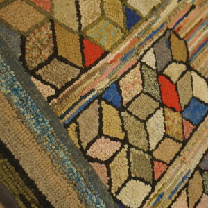 High-texture hooked rug detail showing variegated geometric and striped patterns on wood floor.