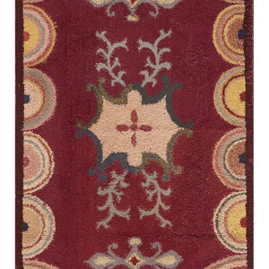 A textured maroon rug features a multicolor geometric and floral central medallion with semicircles around the border.