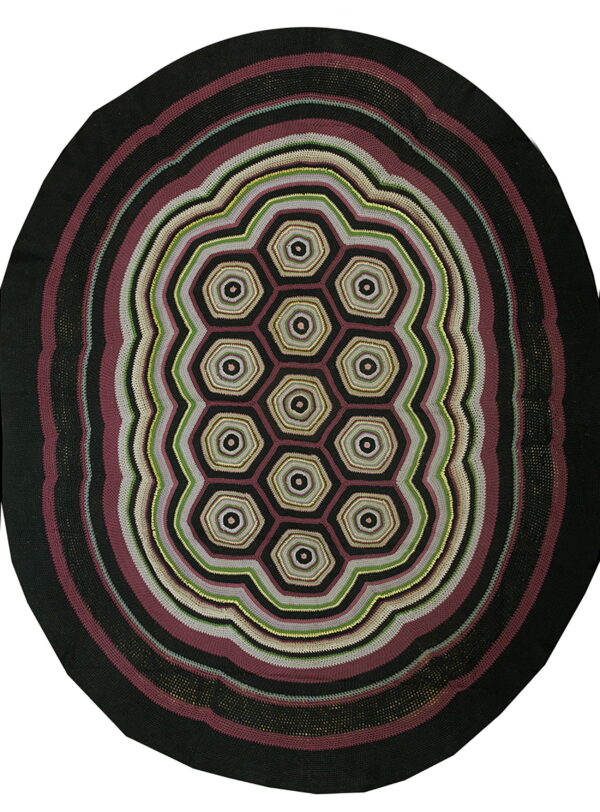 Round rug with black, burgundy, gray, and green concentric rings surrounding a central honeycomb pattern.