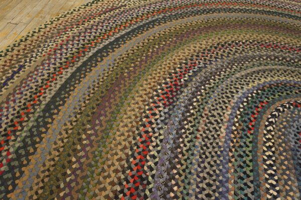 Close-up of a multicolored, braided rug featuring concentric rows on light wood plank flooring.