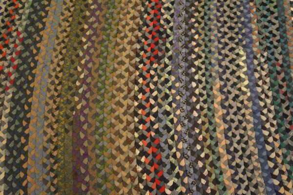 Muted multicoloured braids form distinct vertical columns in gray, green, tan, blue, and red accents.