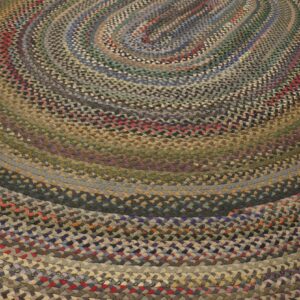 A braided oval rug features concentric rings in multicolored, earthy tones like blue, green, brown, and red.