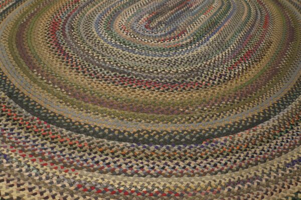 A braided oval rug features concentric rings in multicolored, earthy tones like blue, green, brown, and red.
