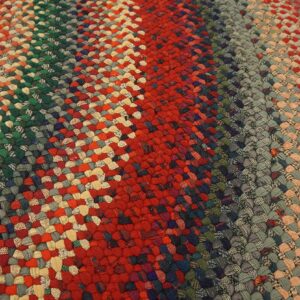 Close view of a multicolored braided rug with red, green, and gray stripes on distressed wood flooring.