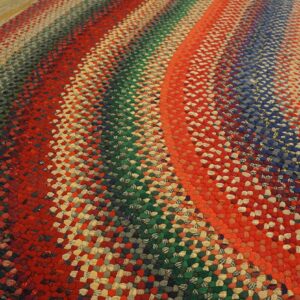 Textured braided rug in vibrant concentric stripes of red, blue, green, and mixed colors on wood flooring.