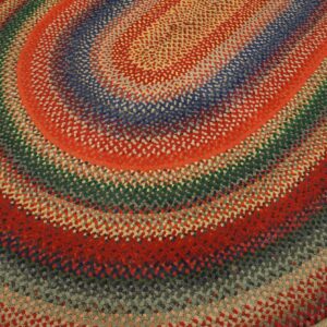 Highly textured braided rug with colorful concentric oval rings in red, blue, green, and gray tones.