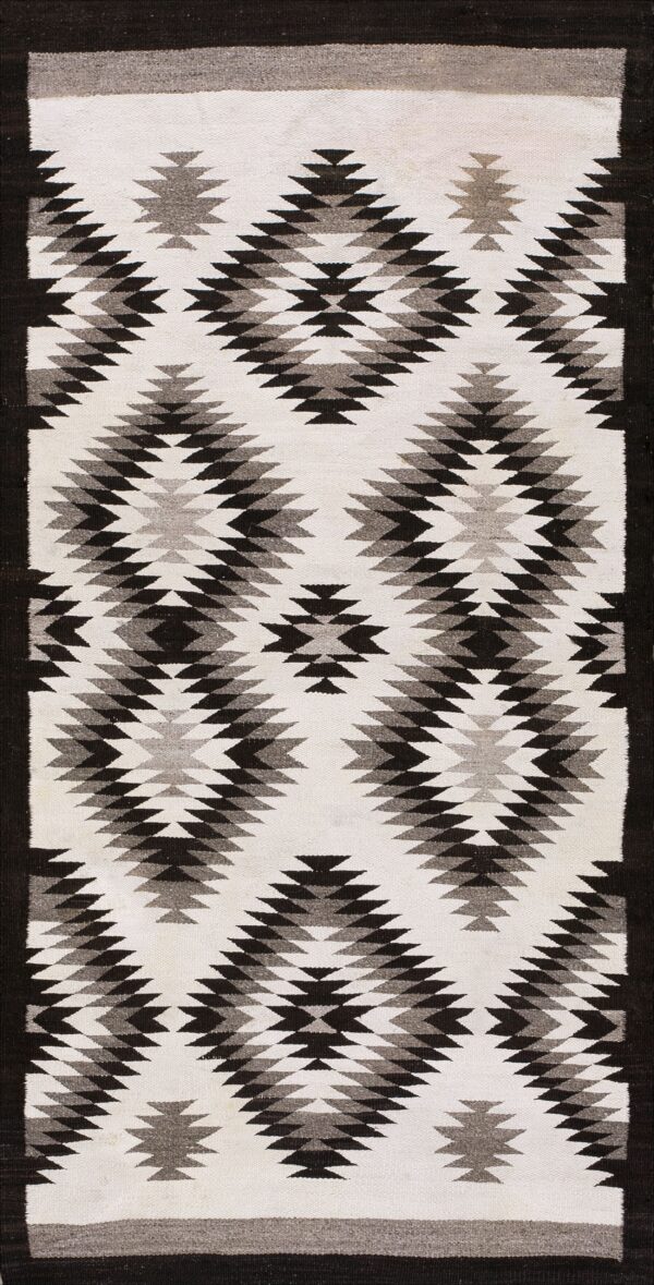 Flatweave rug with a black and gray serrated diamond pattern on a white background and dark border.