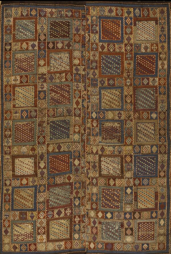 Flatwoven rug featuring a dense geometric patchwork of red, blue, brown, and gold squares and diamonds.