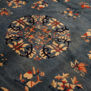 Close-up of a deep blue rug featuring a circular medallion and scattered floral sprays in tan and peach.