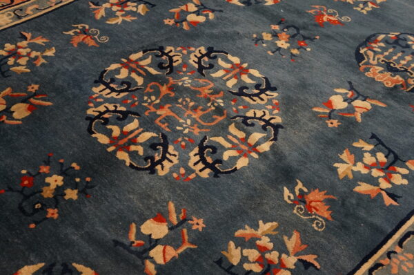 Close-up of a deep blue rug featuring a circular medallion and scattered floral sprays in tan and peach.