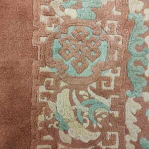 High-pile rug texture showing sculpted traditional patterns in dusty rose, mint green, and cream.