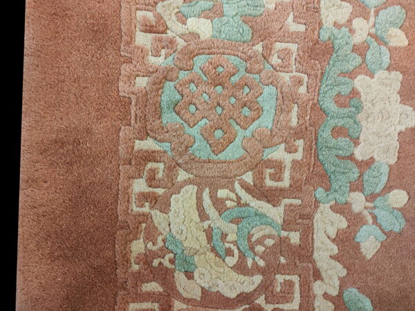 High-pile rug texture showing sculpted traditional patterns in dusty rose, mint green, and cream.