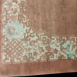 Plush mauve rug corner with an embossed border of ivory, dusty rose, and light teal floral designs.