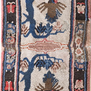 High-pile rug with a cream field, blue trees, and deer, framed by black and pink borders.