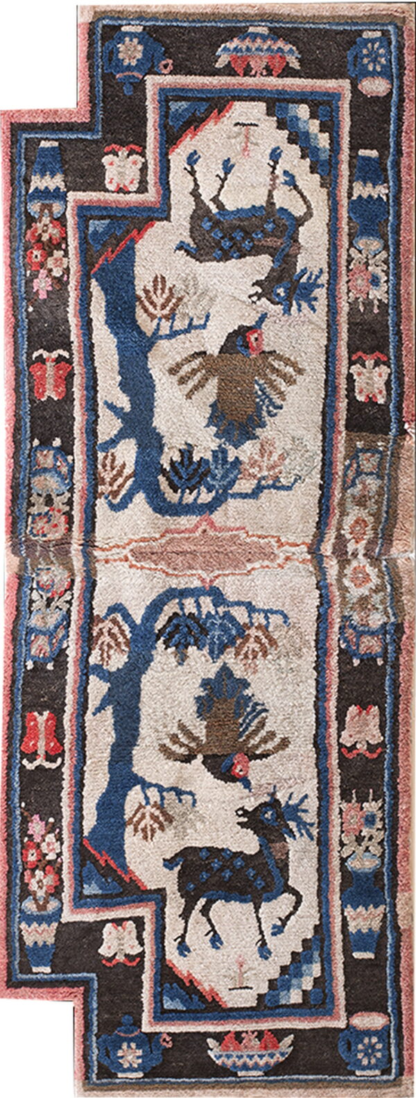 High-pile rug with a cream field, blue trees, and deer, framed by black and pink borders.