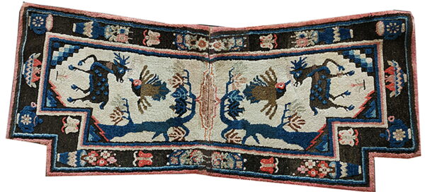 Notched, folded textile displaying symmetrical animal patterns in blue, cream, dark brown, and coral colors.