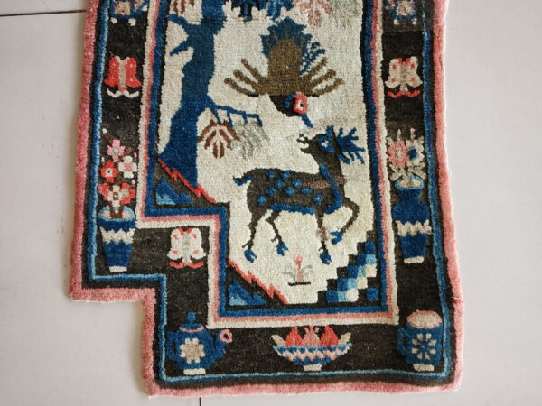 High-pile, dark-bordered rug featuring blue and brown animal figures on a cream ground with pink and rust accents.