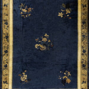 Navy blue rug with scattered golden floral designs and a wide cream and olive botanical border.