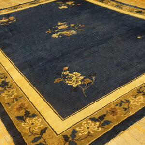 Navy blue rug with scattered gold florals and a wide yellow and olive patterned border on hardwood flooring.