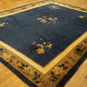 Dark blue rug with scattered floral bouquets and a wide golden botanical border on wood floors.