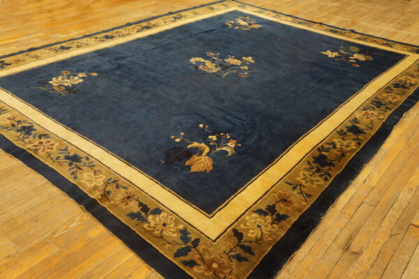 Dark blue rug with scattered floral bouquets and a wide golden botanical border on wood floors.