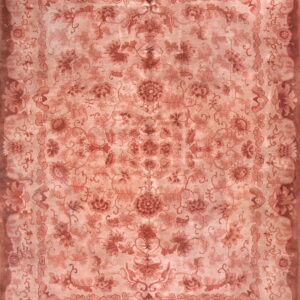 An overhead view of a large rug featuring an ornate floral design in faded salmon and terracotta tones.