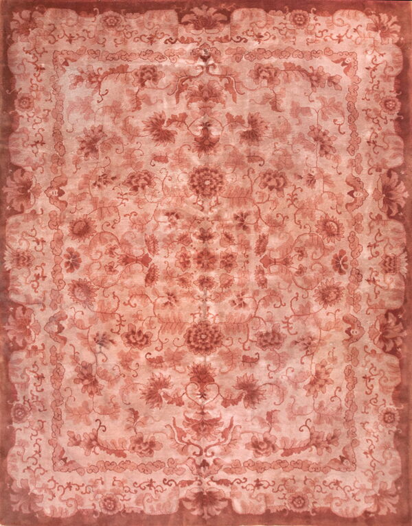 An overhead view of a large rug featuring an ornate floral design in faded salmon and terracotta tones.