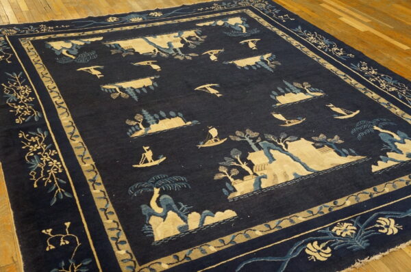 Dark blue rug with a light blue and tan landscape pattern displayed on wooden planks.