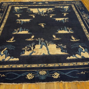 Navy blue pictorial rug with tan and light blue landscape designs sits on bright wood flooring.