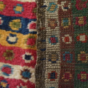 High-pile magenta, blue, and yellow stripes meet a tightly woven geometric pattern in earthy, multicolored tones.