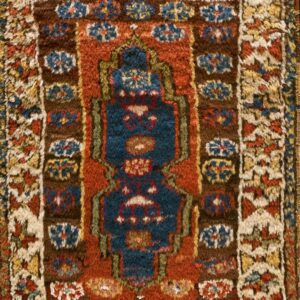 Shaggy, textured rug featuring a navy blue center design bordered by rust, brown, and cream geometric motifs.