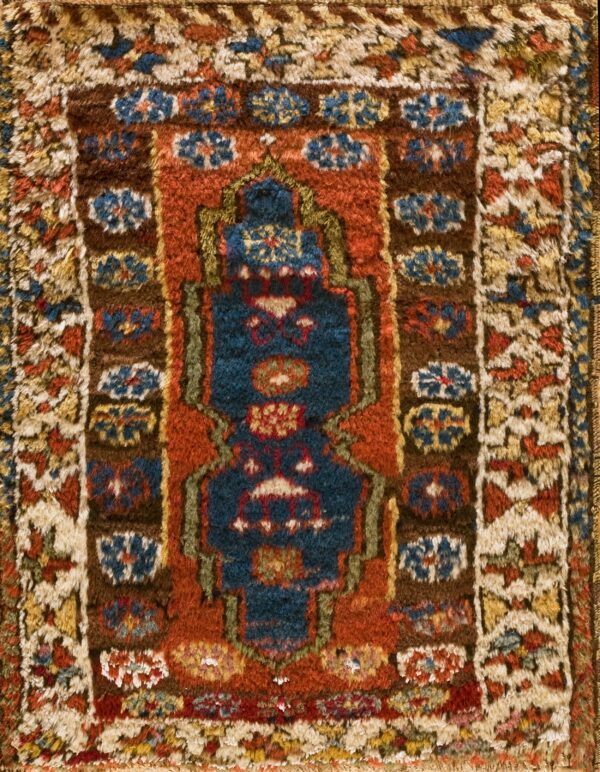 Shaggy, textured rug featuring a navy blue center design bordered by rust, brown, and cream geometric motifs.