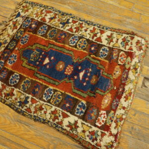 High-pile traditional rug with a navy center, rust field, and multicolor borders on worn wood flooring.
