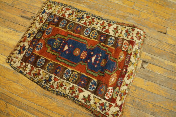 High-pile traditional rug with a navy center, rust field, and multicolor borders on worn wood flooring.