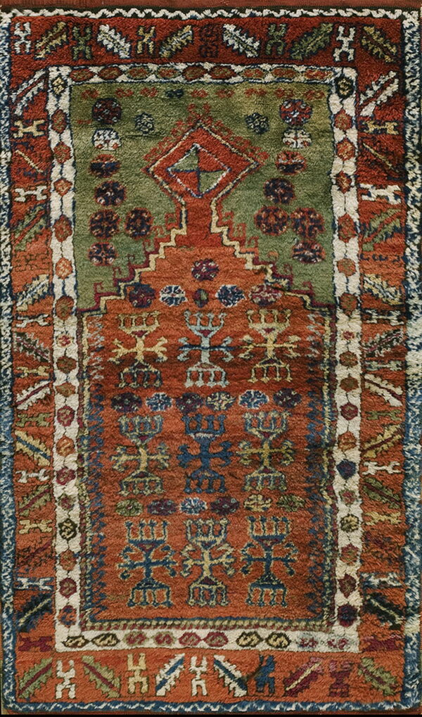 High-pile rug with geometric patterns, featuring a green field within a rust and blue stepped arch design.